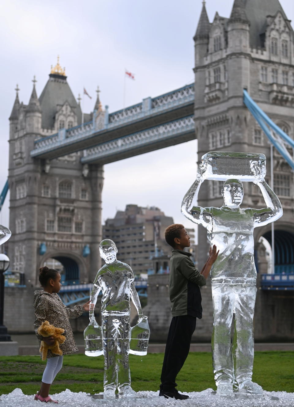 Alice, 5 and Alex, 10, view melting ice sculptures depicting people collecting clean water, as environmental and public health campaign group WaterAid highlights the threat posed globally by climate change to healthy water supplies, near Tower Bridge, in London, Britain, September 15, 2021. REUTERS/Toby Melville