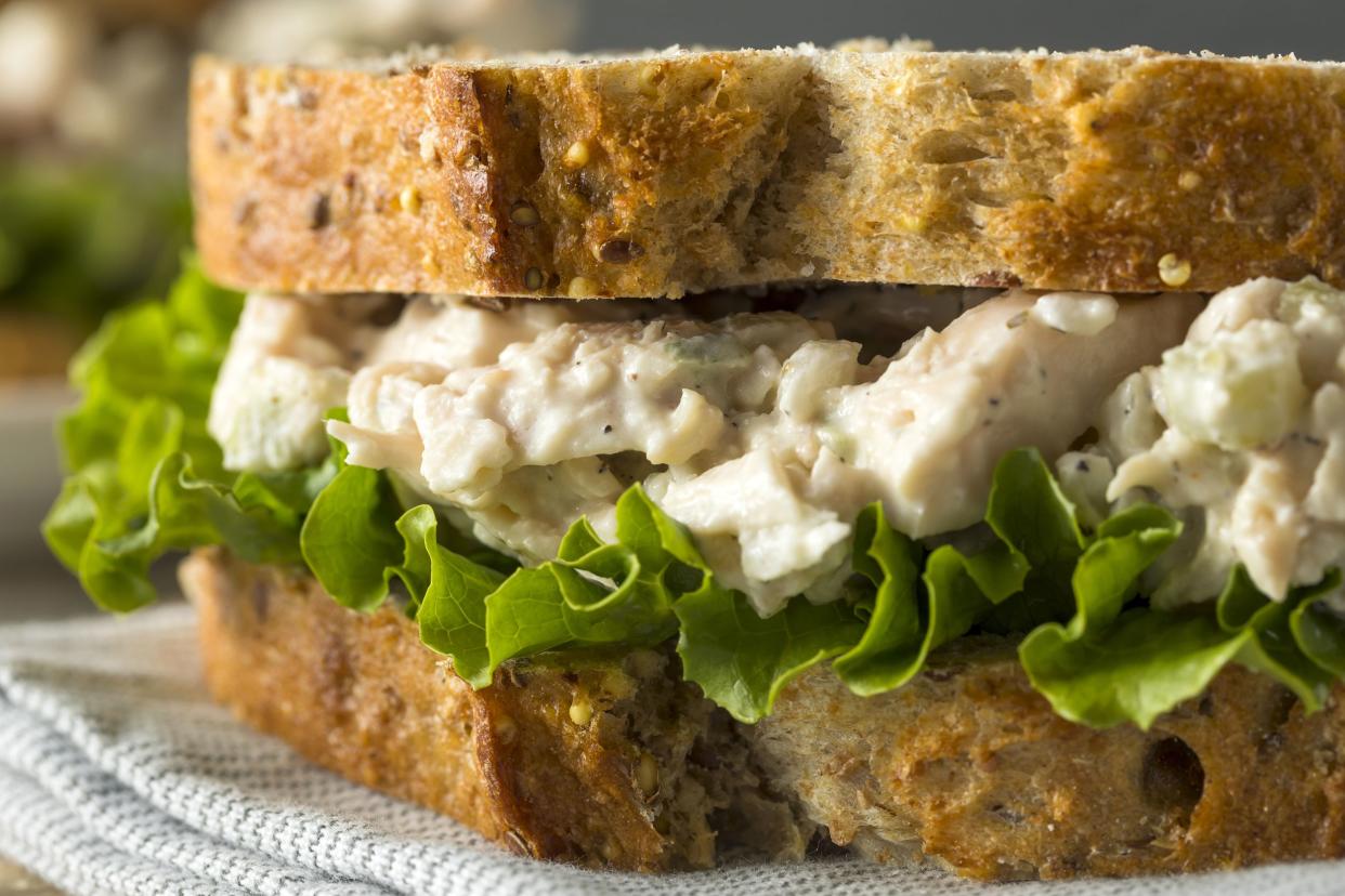 Closeup of classic chicken salad on two pieces of whole wheat bread on a blue and white napkin with a blurred background