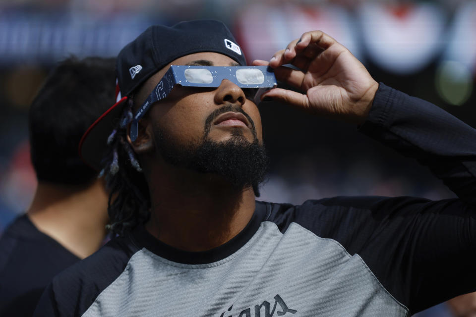 Cleveland Guardians pitcher Emmanuel Clase uses special glasses to watch the total solar eclipse, Monday, April 8, 2024, in Cleveland. (AP Photo/Ron Schwane)