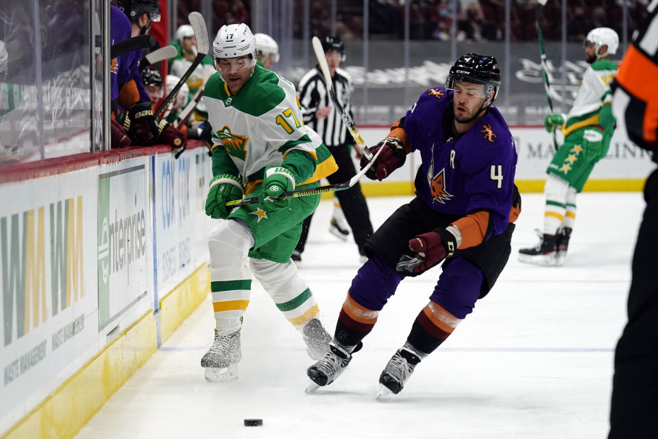 Minnesota Wild left wing Marcus Foligno (17) and Arizona Coyotes defenseman Niklas Hjalmarsson (4) fight for the puck in the first period during an NHL hockey game, Saturday, March 6, 2021, in Glendale, Ariz. (AP Photo/Rick Scuteri)