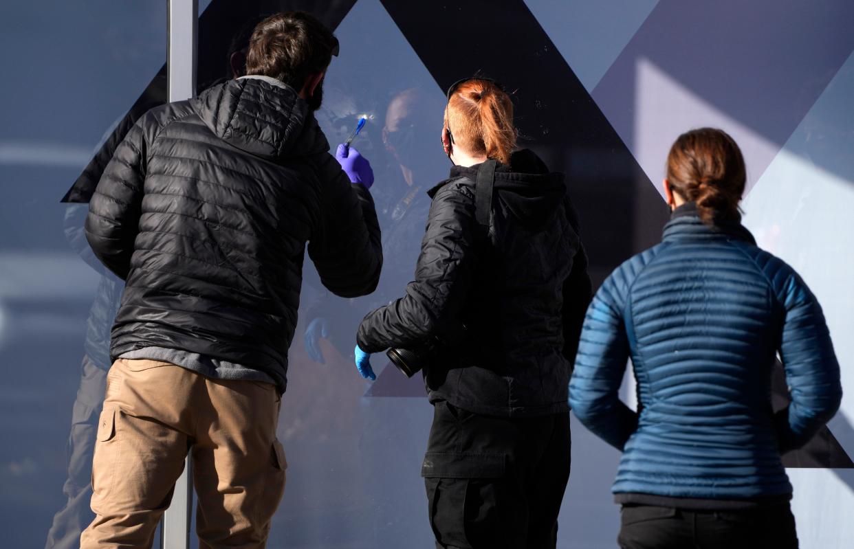 Investigators chart evidence from a window outside an Xfinity store Tuesday, Dec. 28, 2021, in Denver Lakewood, Colo., one of the scenes of a shooting spree that left several people dead, including the suspected shooter Monday evening.