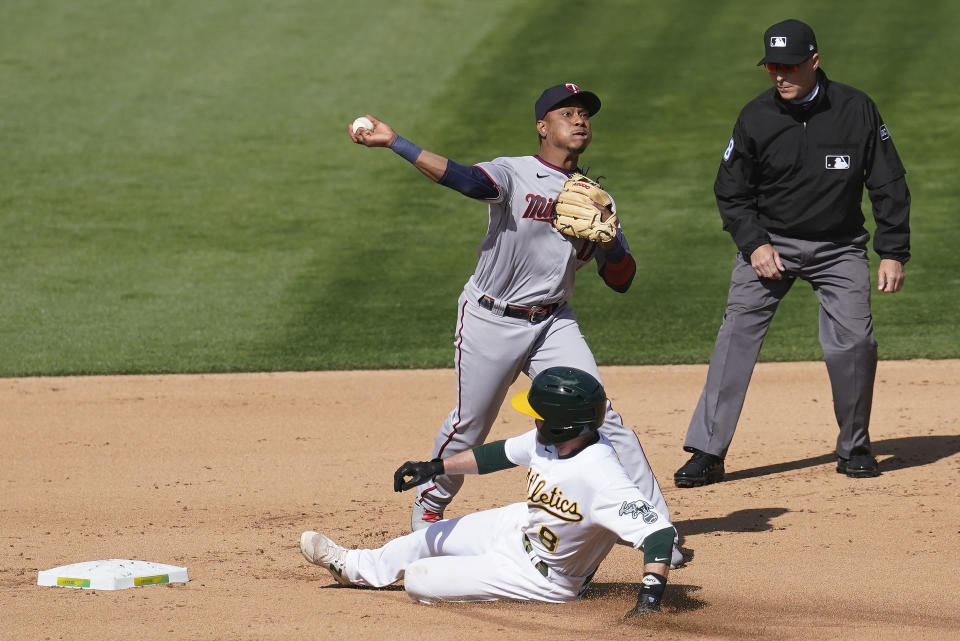 Minnesota Twins shortstop Jorge Polanco, top, throws to first base after forcing out Oakland Athletics' Jed Lowrie at second base on a double play hit into by Matt Olson during the third inning of the first baseball game of a doubleheader in Oakland, Calif., Tuesday, April 20, 2021. (AP Photo/Jeff Chiu)