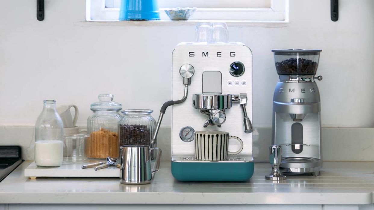 Lifestyle image of the The Smeg MiniPro Coffee Machine and Smeg Espresso Coffee Grinder sitting on a kitchen counter. 