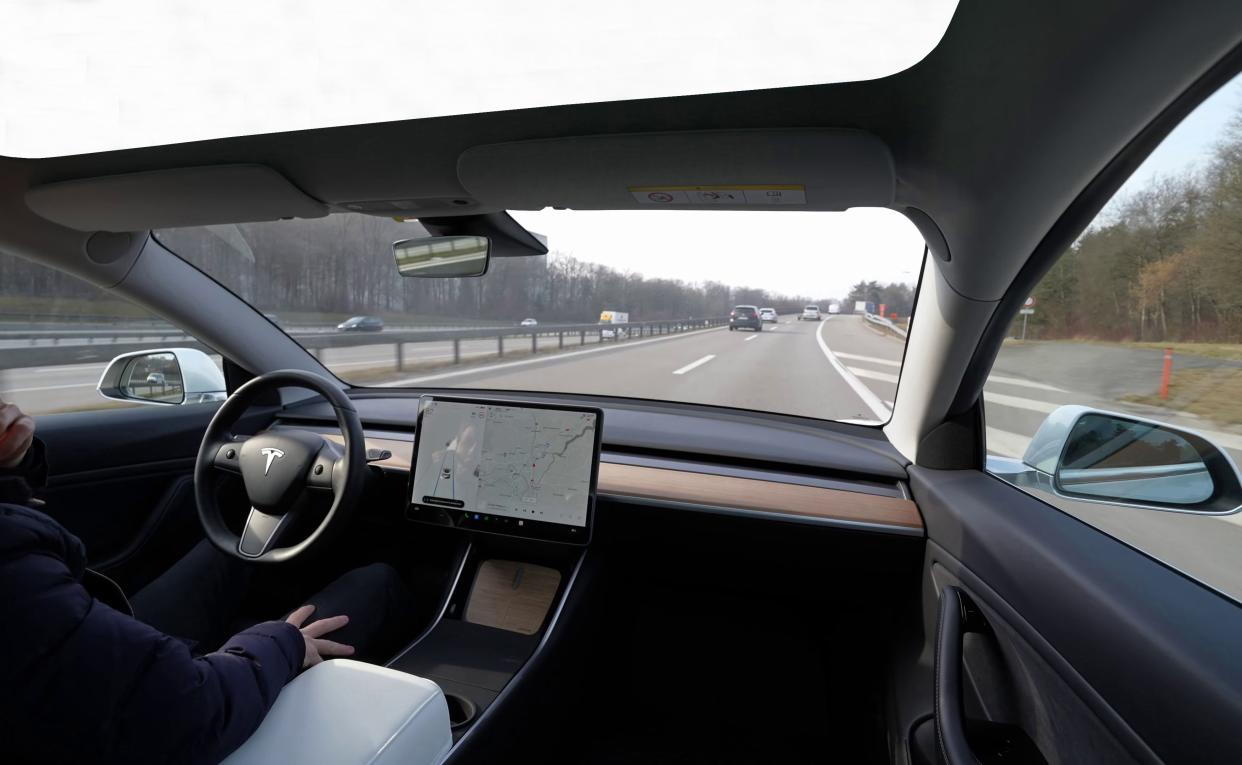 Lombardia, Italy - January 17, 2022: Close-up of a Tesla Model 3, with a glass roof. driving down a highway on autopilot. And a man inside, resting, with one hand on his face and the other on his leg.