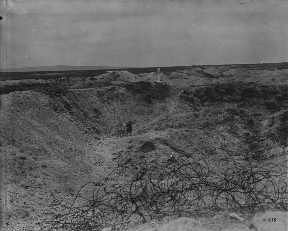 <p>A soldier walks through Grange Crater, blown by Canadian tunnellers, in a photo taken in July 1917. Photo from Library and Archives Canada. </p>