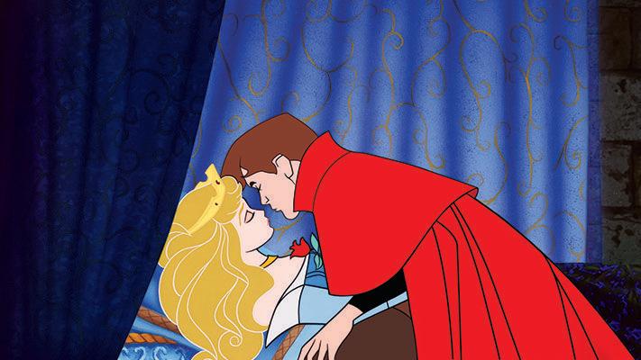 the prince leans in to give a kiss to an enchanted princess aurora in a scene from sleeping beauty