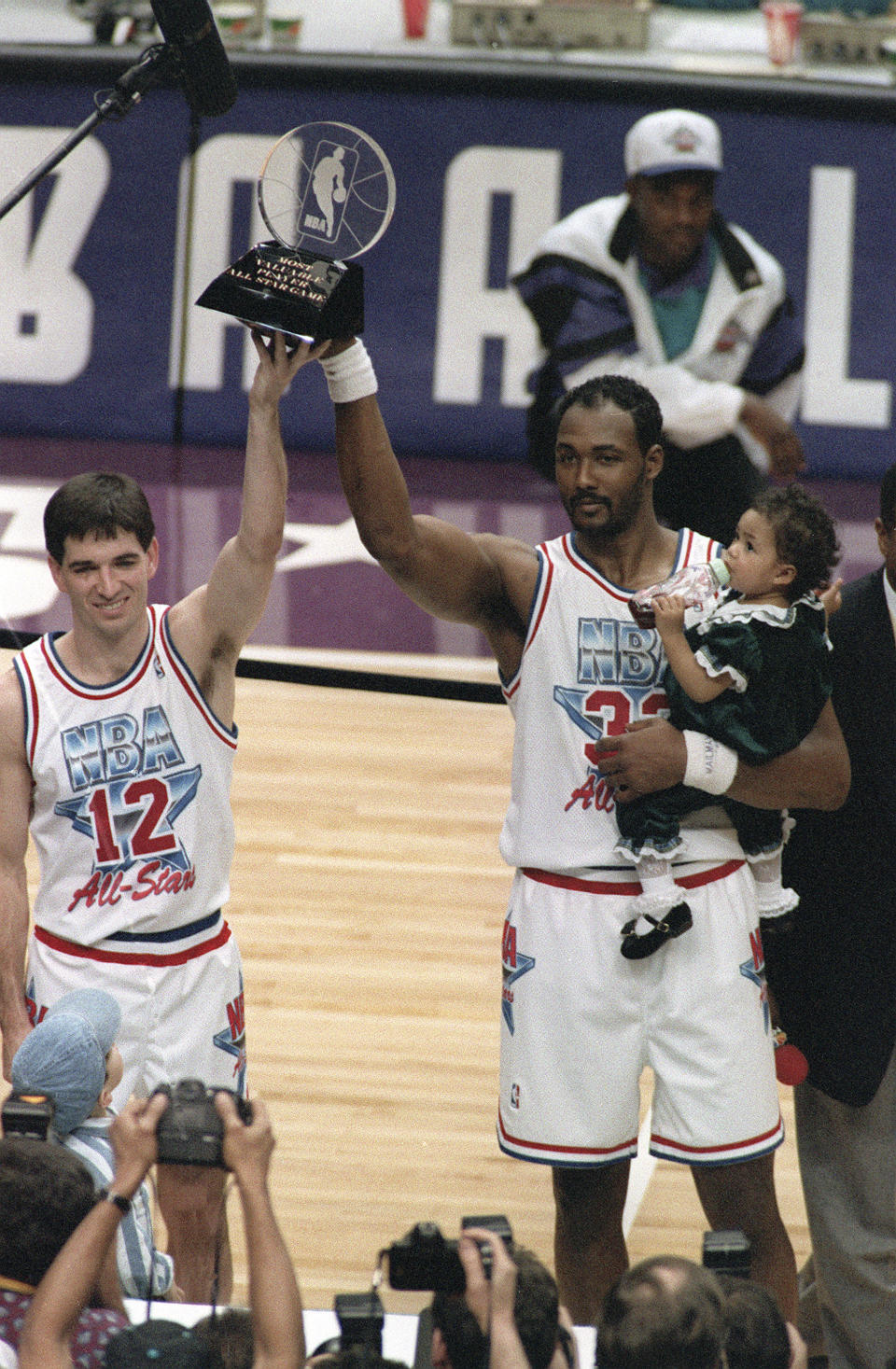 FILE - Utah Jazz teammates and co-Most Valuable Player winners John Stockton, left, and Karl Malone hold up the All-Star MVP trophy after playing for the West team, which won the 43rd NBA All-Star game 135-130 in Salt Lake City, on Feb. 21, 1993. Malone holds his daughter, Kaydee. Salt Lake City's hosting of this weekend's NBA All-Star game for the first time in three decades gives Utah another opportunity to reshape a long-held belief that the state is odd or peculiar — a years-long push that Jazz owner Ryan Smith and many other influential state leaders have prioritized. (AP Photo/Roberto Borea, File)