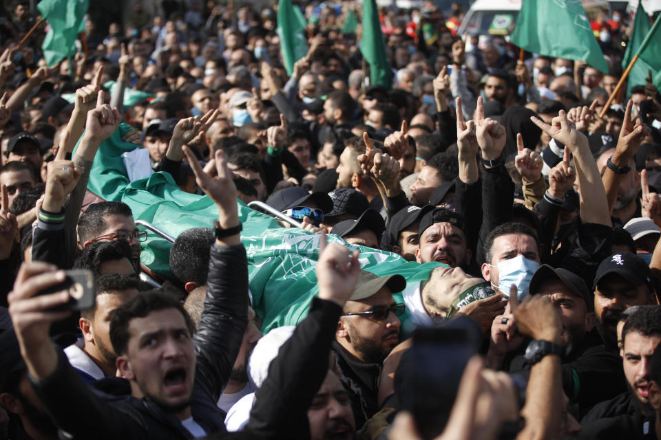 Palestinian mourners shout slogans as they carry the body of a Hamas member who was killed after gunfire erupted last Sunday during a Hamas-organized funeral in a tense Palestinian refugee camp, during his funeral procession in the southern port city of Sidon, Lebanon, Tuesday, Dec. 14, 2021. (AP Photo/Mohammed Zaatari)