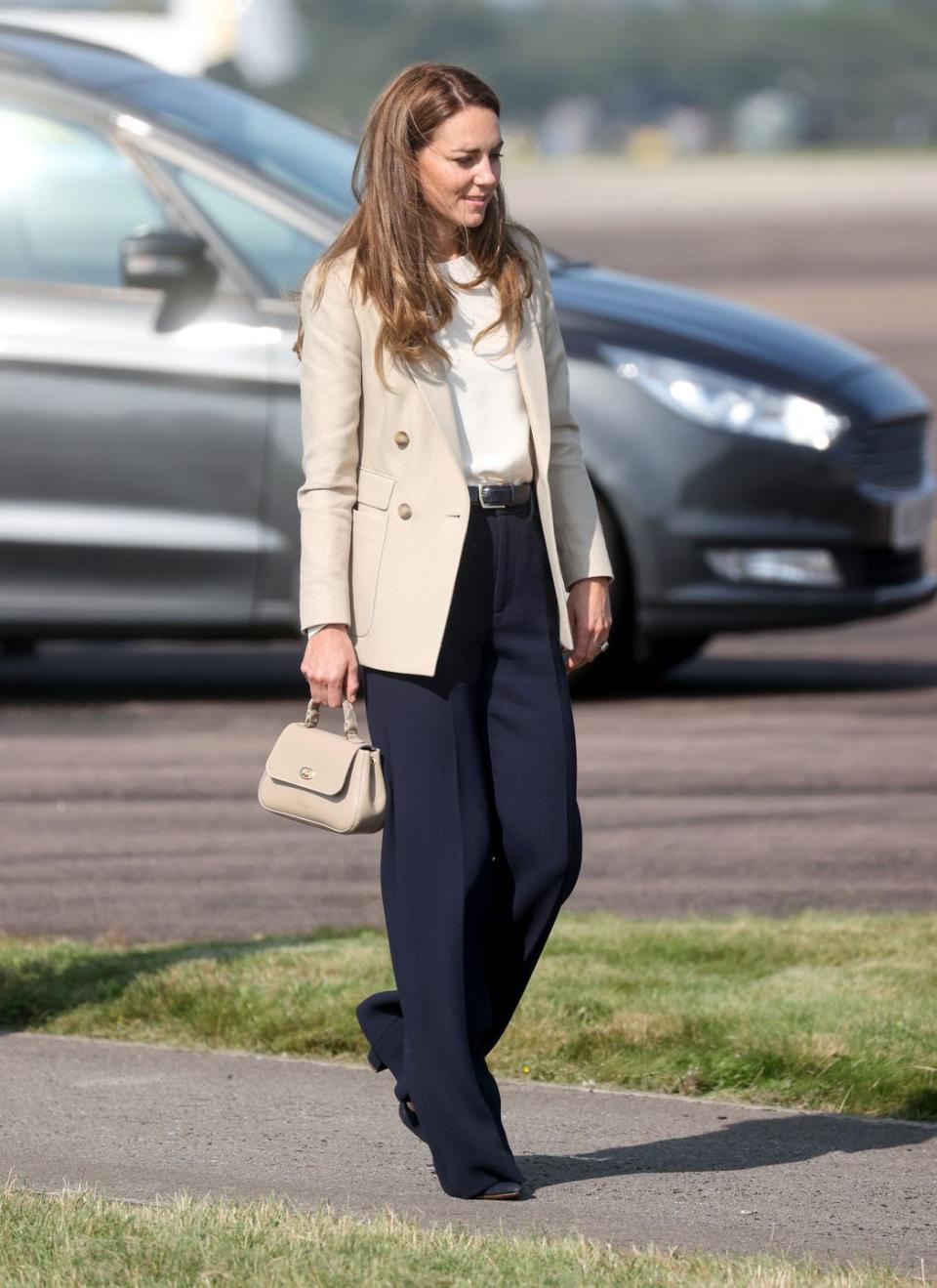 <p>The Duchess of Cambridge returned to royal duties after her summer break and she did so sporting the perfect back-to-work outfit. While <a href="https://www.townandcountrymag.com/society/tradition/a37596711/kate-middleton-cream-blazer-navy-trousers-raf-visit-photos/" rel="nofollow noopener" target="_blank" data-ylk="slk:visiting a Royal Air Force military base;elm:context_link;itc:0;sec:content-canvas" class="link ">visiting a Royal Air Force military base</a>, she wore a <a href="https://go.redirectingat.com?id=74968X1596630&url=https%3A%2F%2Fwww.reiss.com%2Fp%2Fdouble-breasted-twill-blazer-womens-larsson-in-neutral-brown%2F&sref=https%3A%2F%2Fwww.townandcountrymag.com%2Fstyle%2Ffashion-trends%2Fnews%2Fg1633%2Fkate-middleton-fashion%2F" rel="nofollow noopener" target="_blank" data-ylk="slk:neutral Reiss blazer;elm:context_link;itc:0;sec:content-canvas" class="link ">neutral Reiss blazer</a> and wide leg navy trousers. </p>