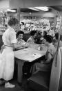 <p>In this photo, a waitress brings "Uranium Sundae" to a table. The sundae was named after Salt Lake City, Utah's booming uranium industry.</p>
