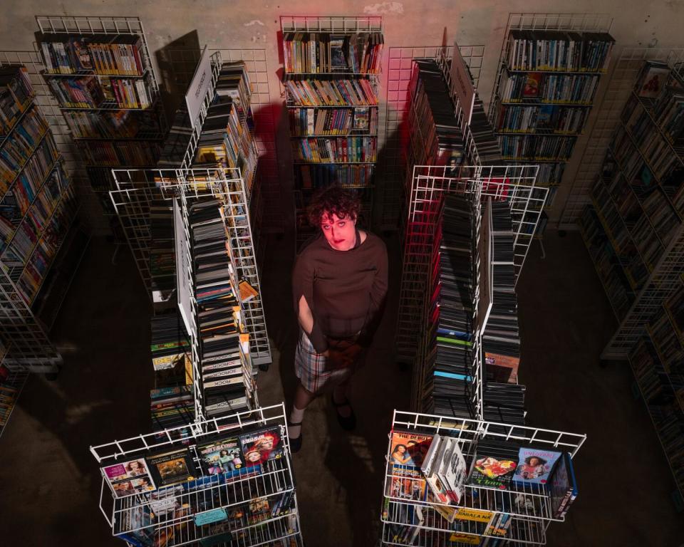 A filmmakers stands amid rows of thousands of DVDs and Blu-rays.