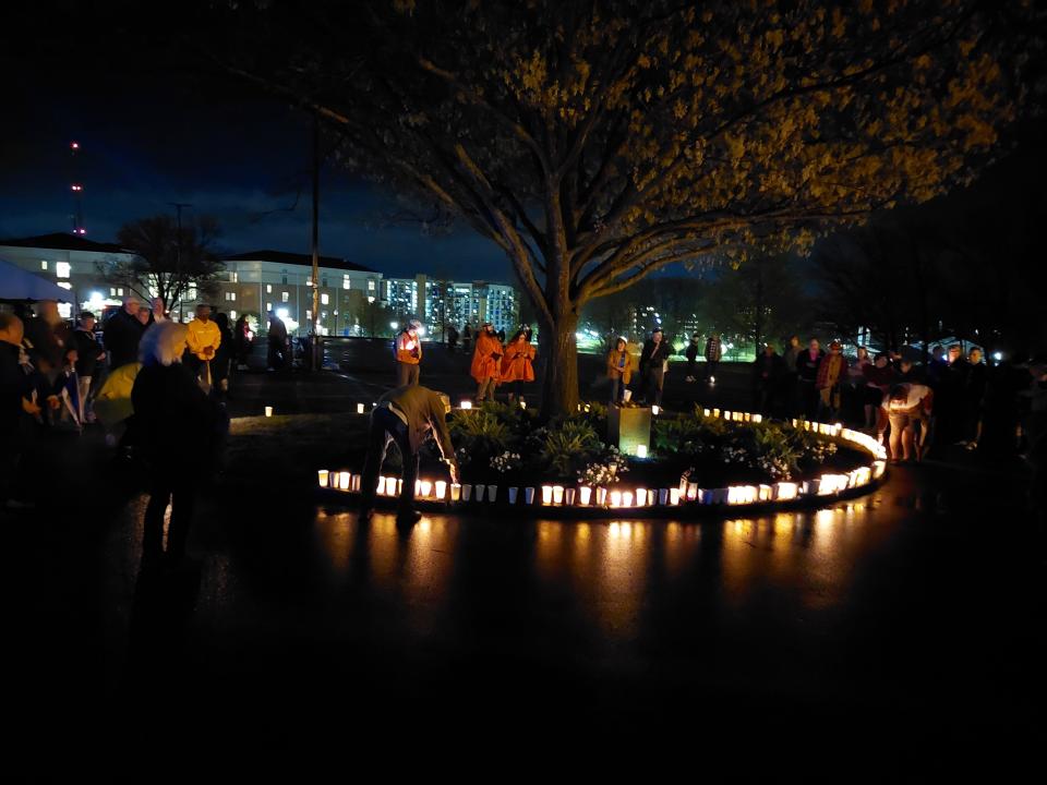 In 2022, Participants of the candlelight march gather around the Taylor Hall memorial for the victims of the May 4, 1970, shooting, placing their candles at the base of the tree.