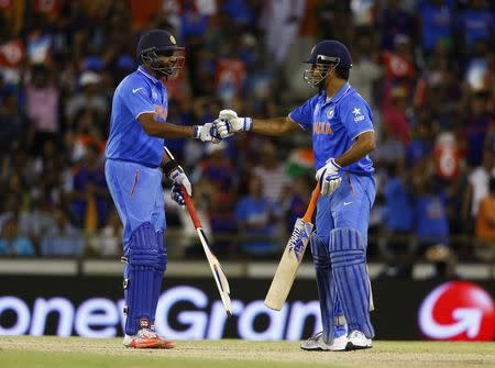 Indian batsmen Ravichandran Ashwin (L) and MS Dhoni fist-bump after 6 runs were scored during their partnership in which they won over the West Indies at the Cricket World Cup in Perth, March 6, 2015. REUTERS/David Gray