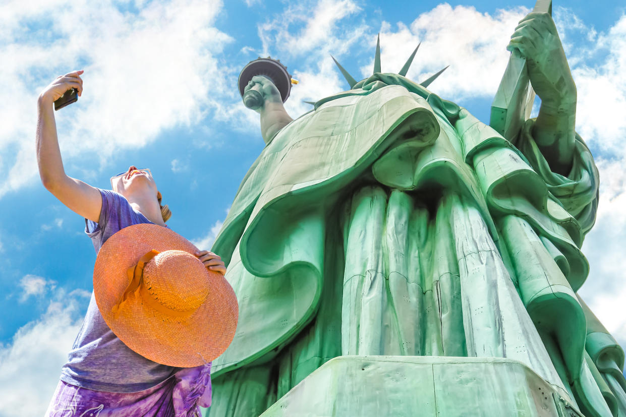 Una turista se toma un selfie junto a la Estatua de la Libertad. 