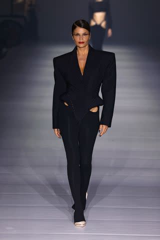 <p>Estrop/Getty</p> Helena Christensen walks the runway during Mugler's Spring 2024 show.