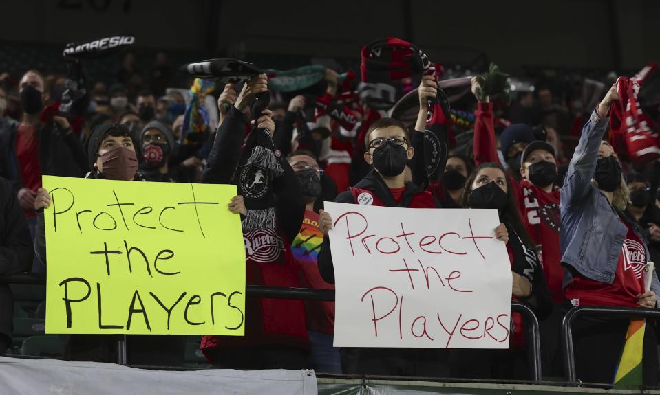 Portland Thorns fans hold signs during the first half of the team's NWSL soccer match against the Houston Dash in Portland, Ore., Wednesday, Oct. 6, 2021. Players stopped on the field in the first half of Wednesday night's National Women’s Soccer League games and linked arms in a circle to demonstrate solidarity with two former players who came forward with allegations of sexual harassment and misconduct against a prominent coach. (AP Photo/Steve Dipaola)