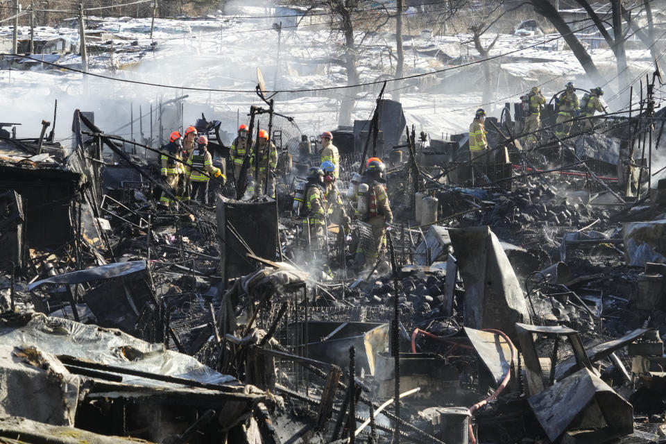 Firefighters clean up the site of a fire at Guryong village in Seoul, South Korea, Friday, Jan. 20, 2023. A fire spread through a neighborhood of densely packed, makeshift homes in South Korea's capital Friday morning. (AP Photo/Ahn Young-joon)