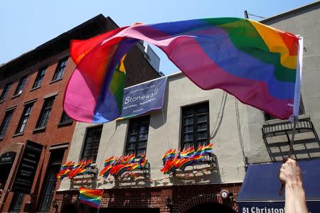 FILE PHOTO: A participant waves a pride flag as they pass the Stonewall Inn during the annual NYC Pride parade in New York City, New York, U.S., June 26, 2016. REUTERS/Brendan McDermid