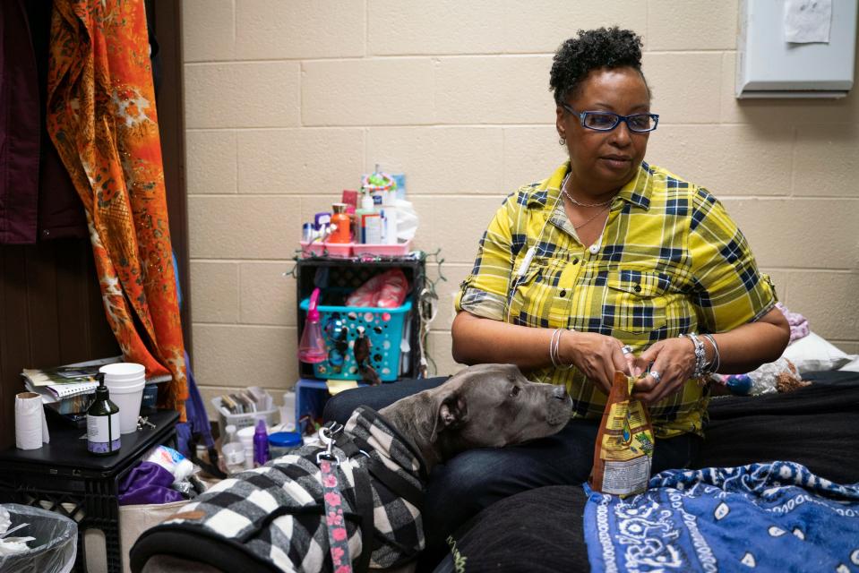 Tonya Hogan, 50, opens a treat bag for her dog Pepper inside their room at Harbor Light Salvation Army in Detroit on Thursday, March 9, 2023. On most days, Pepper drags her feet to resist going inside the tiny room with no windows where they have lived for over a year while Hogan seeks to find secure housing.