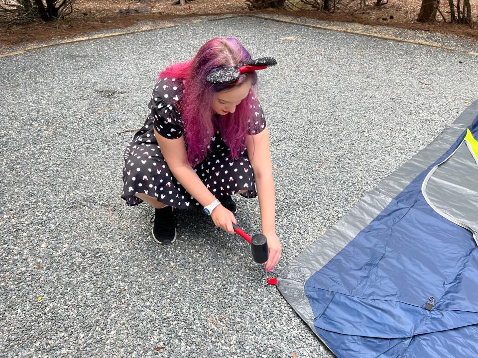 the writer using a rubber mallet to put a tent down