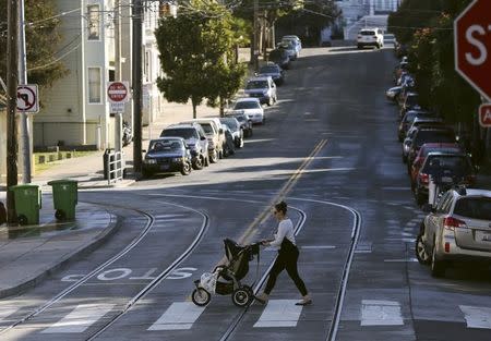 A woman walks with a child stroller across a pedestrian crossing, in San Francisco, California February 19, 2014. REUTERS/Robert Galbraith