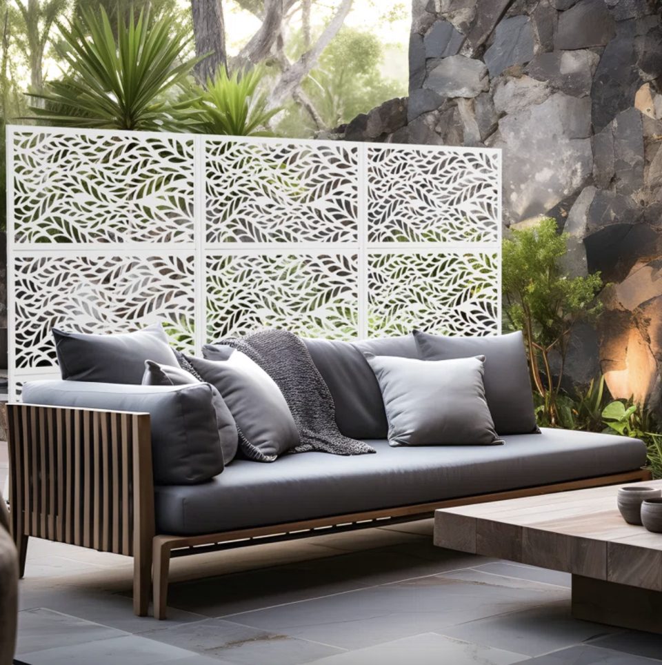 Outdoor furniture setting with a modern sofa, cushions, and decorative panel backdrop