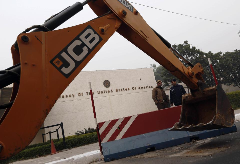 Policemen stand next to a bulldozer removing the security barriers in front of the U.S. embassy in New Delhi