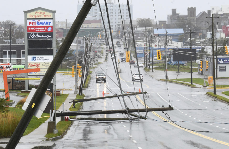 Downed power poles block a road in Glace Bay, Nova Scotia, on Sunday, Sept. 25, 2022. A day after post-tropical storm Fiona left a trail of destruction through Atlantic Canada and eastern Quebec, residents of a coastal town in western Newfoundland continued to pick through wreckage strewn across their community, easily the most damaged area in the region. (Vaughan Merchant/The Canadian Press via AP)