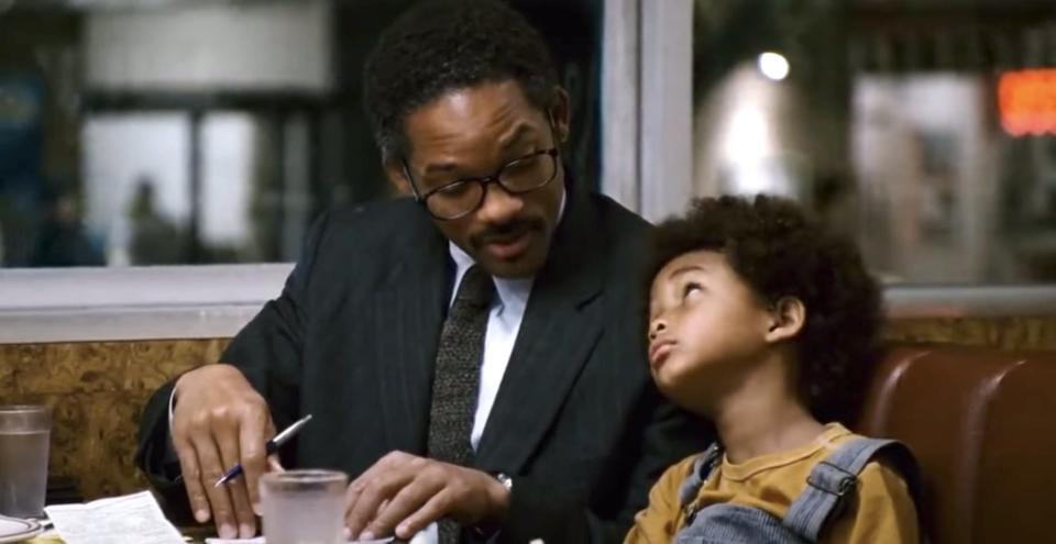 Will Smith and Jaden Smith sitting next to each other at a table in "The Pursuit of Happyness."