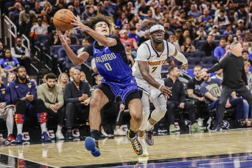 Orlando Magic guard Anthony Black (0) holds on to ball as he is defended by Denver Nuggets guard Reggie Jackson (7) during the second half of an NBA basketball game Wednesday, Nov. 22, 2023, in Orlando, Fla. (AP Photo/Kevin Kolczynski)