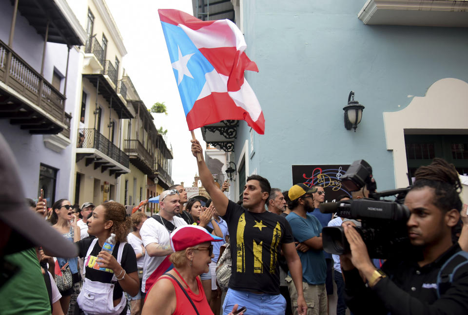 A man waves a Puerto Rican flag during a protest near La Fortaleza governor's residence in San Juan, Puerto Rico, Sunday, July 14, 2019. Protesters are demanding Gov. Ricardo Rosselló step down for his involvement in a private chat in which he used profanities to describe an ex-New York City councilwoman and a federal control board overseeing the island's finance. (AP Photo/Carlos Giusti)