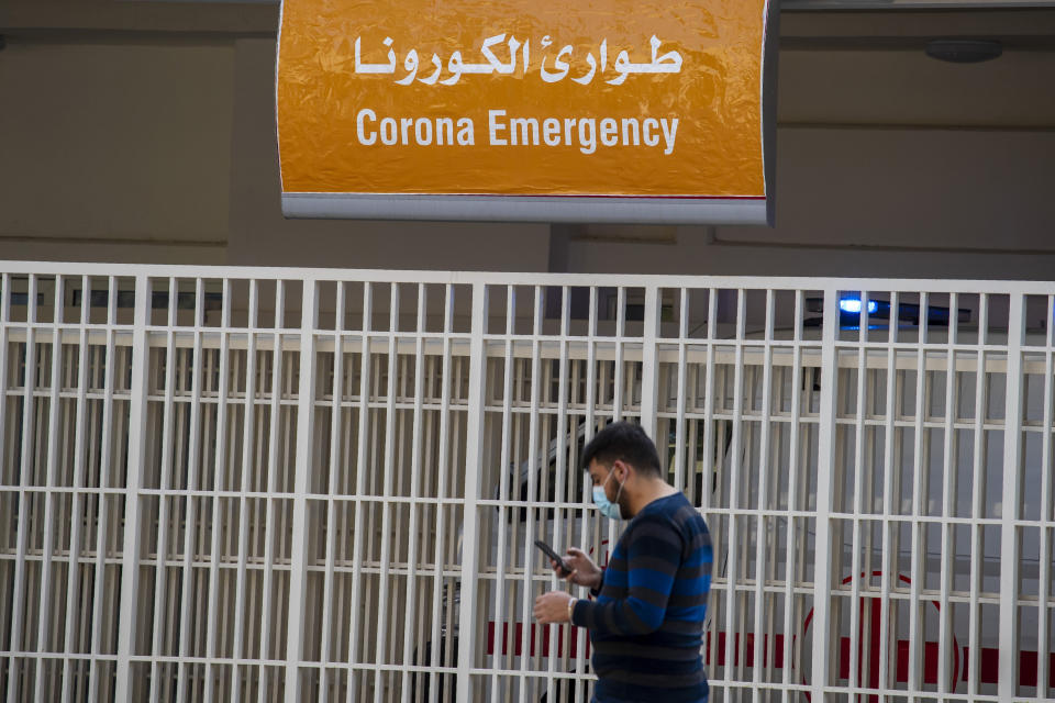 A man wears a mask as he checks his mobile phone while passing the emergency entrance of the government-run Rafik Hariri University Hospital where most of the Lebanese coronavirus cases are treated in Beirut, Lebanon, Thursday, March 26, 2020. The new coronavirus causes mild or moderate symptoms for most people, but for some, especially older adults and people with existing health problems, it can cause more severe illness or death. (AP Photo/Hassan Ammar)