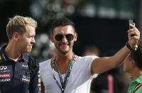 Red Bull Formula One driver Sebastian Vettel of Germany (L) takes a picture with a fan ahead of the third practice session of the Singapore F1 Grand Prix at the Marina Bay street circuit in Singapore September 21, 2013. REUTERS/Edgar Su (SINGAPORE - Tags: SPORT MOTORSPORT F1)