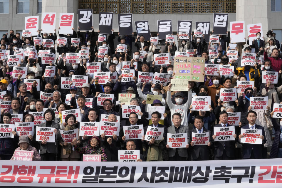 South Korean opposition lawmakers and civic groups stage a rally against the South Korean government's plan over the issue of compensation for forced labors at the National Assembly in Seoul, South Korea, Tuesday, March 7, 2023. South Korean President Yoon Suk Yeol on Tuesday defended his government's contentious plan to use local funds to compensate Koreans enslaved by Japanese companies before the end of World War II, saying it's crucial for Seoul to build future-oriented ties with its former colonial overlord. The signs read "Out with Yoon Suk Yeol's Humiliating Diplomacy." (AP Photo/Ahn Young-joon)