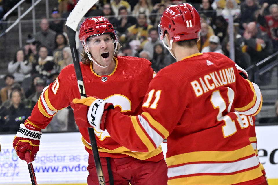 Calgary Flames center Blake Coleman (20) and center Mikael Backlund (11) celebrate a goal against the Vegas Golden Knights during the first period of an NHL hockey game Saturday, Jan. 13, 2024, in Las Vegas. (AP Photo/David Becker)