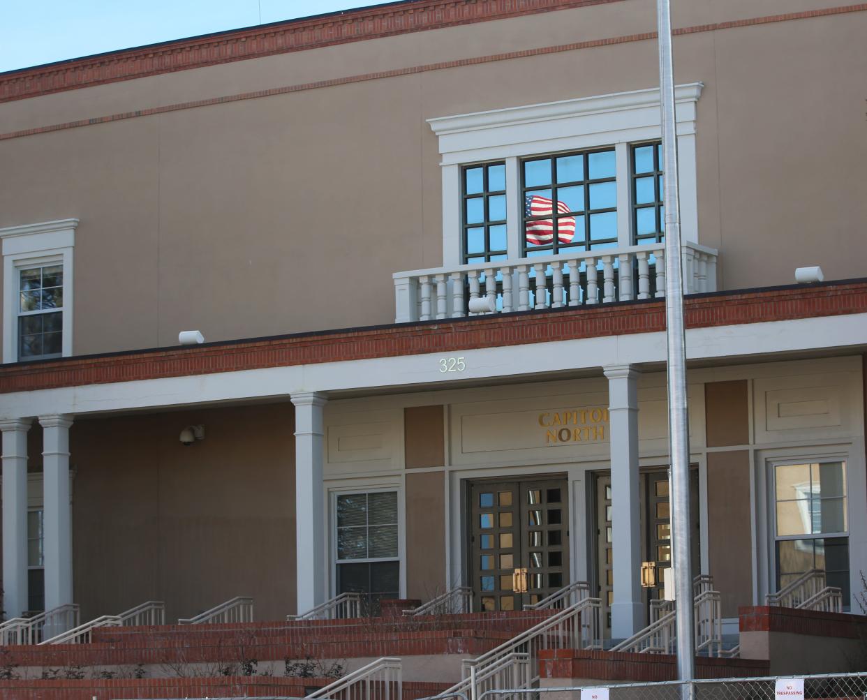 The American flag is reflected in a window of the Roundhouse, New Mexico's capitol building in Santa Fe, on Sunday, Jan. 17, 2021.