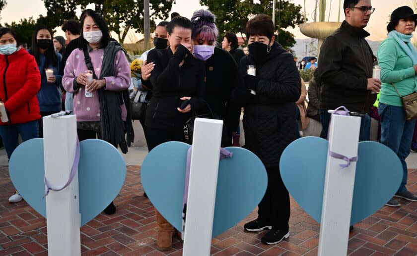 A woman is comforted while grieving as she reads the names of eleven people killed in a mass shooting written on crosses and displayed during a candlelight vigil in front of the City Hall in Monterey Park, California, on January 24, 2023. - Huu Can Tran, the 72-year-old Asian immigrant who killed 11 people before shooting himself as police moved in on him; was once a regular at the California dance club where a tragic gun massacre unfolded. Tran used a semi-automatic pistol to spray 42 bullets around the Star Ballroom Dance Studio in Monterey Park, an Asian-majority city near Los Angeles. (Photo by Frederic J. Brown / AFP) (Photo by FREDERIC J. BROWN/AFP via Getty Images)