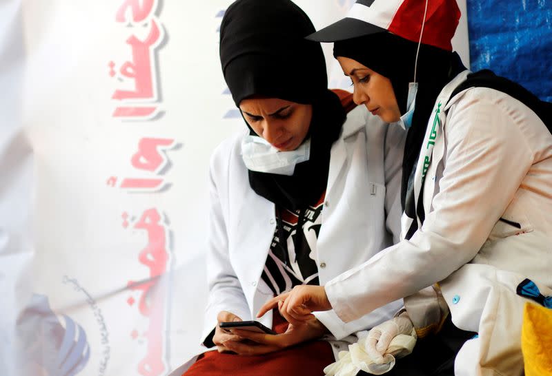 Jassem, 24, an Iraqi nurse browses a mobile phone with her colleague during the break in Baghdad