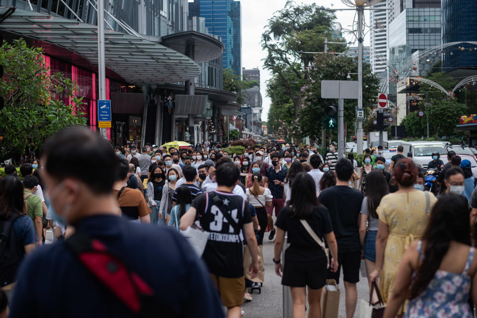 Crowds of people wearing protective face masks walk in Singapore's Orchard Road shopping district on Sunday, 12 December 2021. Singapore authorities reported on 15 December 2021, 2 persons with the Omincron variant of the Covid-19 virus who dined in restaurants along Orchard Road. (Photo by Joseph Nair/NurPhoto via Getty Images)