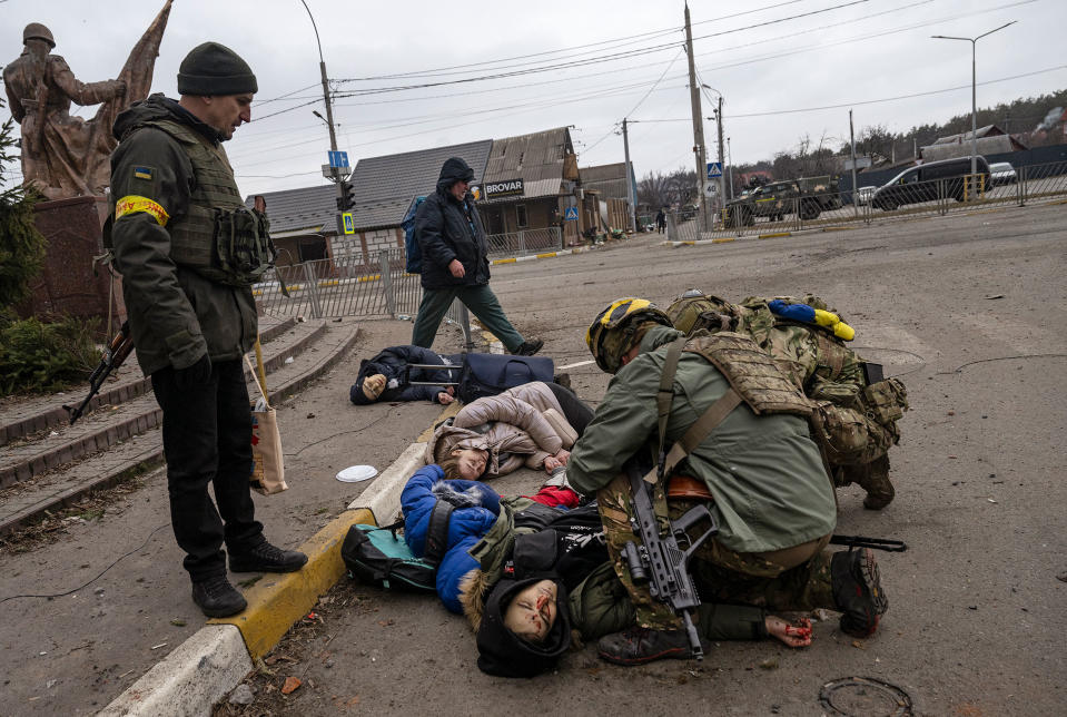 Ukrainian soldiers attend to a group of civilians, including Tetiana Perebyinis and her two children, who were mortally wounded by a Russian mortar round while they evacuated from Irpin, Ukraine, on March 6. A volunteer assisting the family was also killed.<span class="copyright">Lynsey Addario—Getty Images</span>