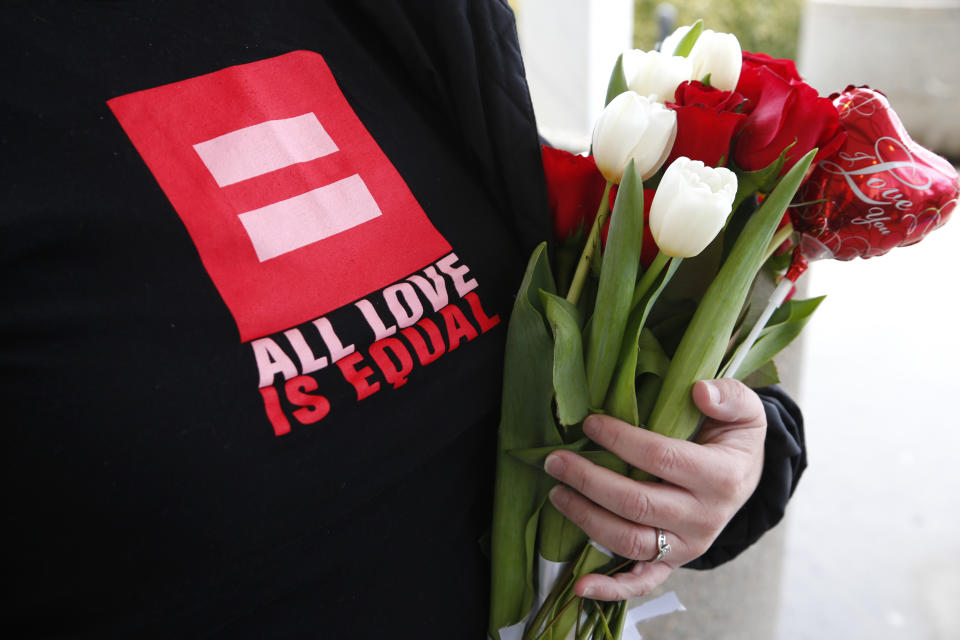 Kim Gillen, holds flowers for friends applying for a marriage license at the Oakland County Clerks office in Pontiac, Mich., Saturday, March 22, 2014. A federal judge has struck down Michigan's ban on gay marriage Friday the latest in a series of decisions overturning similar laws across the U.S. Some counties plan to issue marriage licenses to same-sex couples Saturday, less than 24 hours after a judge overturned Michigan's ban on gay marriage. (AP Photo/Paul Sancya)