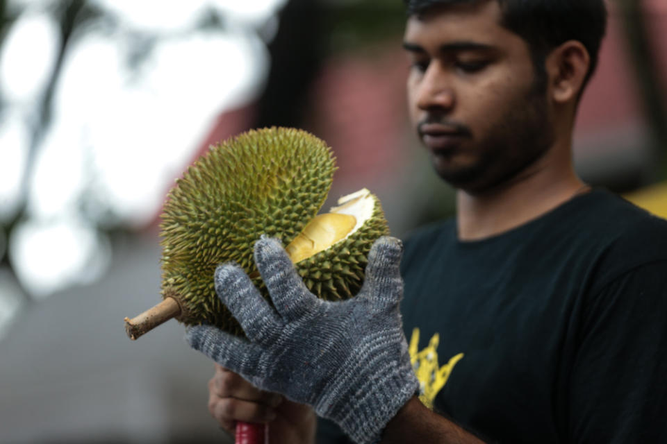 Durian sellers often hit the unripe durian with their knife to ripen the fruit. — Picture by Ahmad Zamzahuri