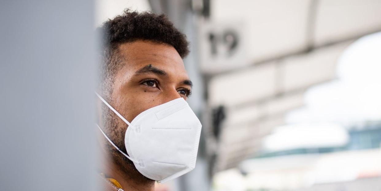 close up of man commuter at the bus station with face mask, coronavirus concept