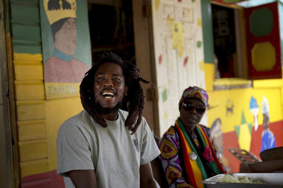 Ras Richie (izquierda) habla con otros miembros de la Fundación Ras Freeman para la Unificación de Rastafari mientras prepara comida para su servicio dominical el 14 de mayo de 2023 en Liberta, Antigua y Barbuda. (AP Foto/Jessie Wardarski)