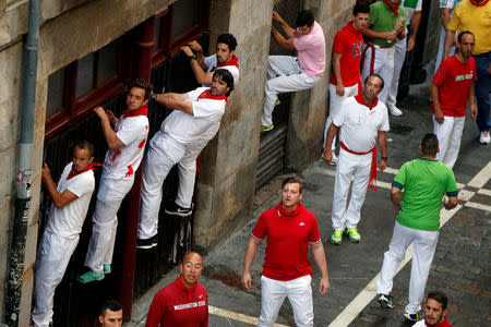 Sergio Colas (3rd L) climbs on a fence to see the bulls coming along Estafeta Street during the third bull run of the San Fermin festival in Pamplona, northern Spain, July 9, 2016. REUTERS/Susana Vera