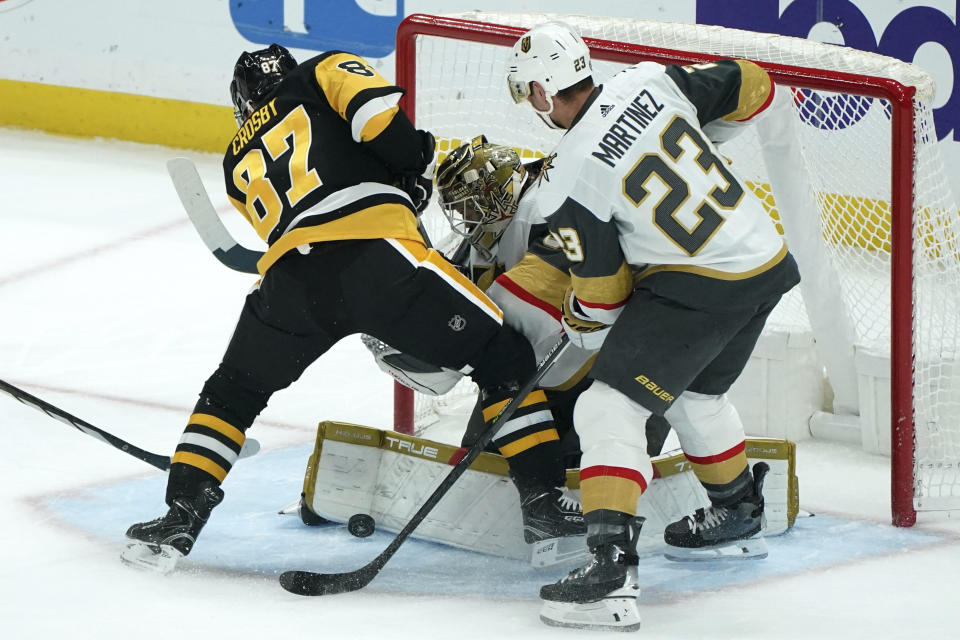 Vegas Golden Knights goaltender Adin Hill blocks a shot in front of Pittsburgh Penguins' Sidney Crosby as Golden Knights' Alec Martinez (23) defends during the first period of an NHL hockey game, Sunday, Nov. 19, 2023, in Pittsburgh. (AP Photo/Matt Freed)