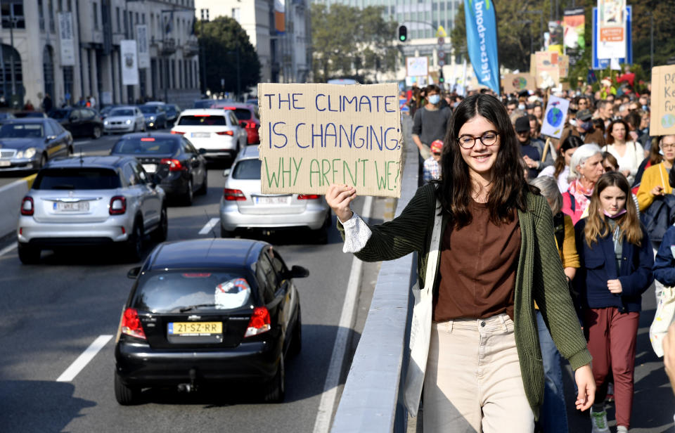 A girl holds up a sign to oncoming traffic as she participates in a climate march and demonstration in Brussels, Sunday, Oct. 10, 2021. Some 80 organizations are joining in a climate march through Brussels to demand change and push politicians to effective action in Glasgow later this month.(AP Photo/Geert Vanden Wijngaert)