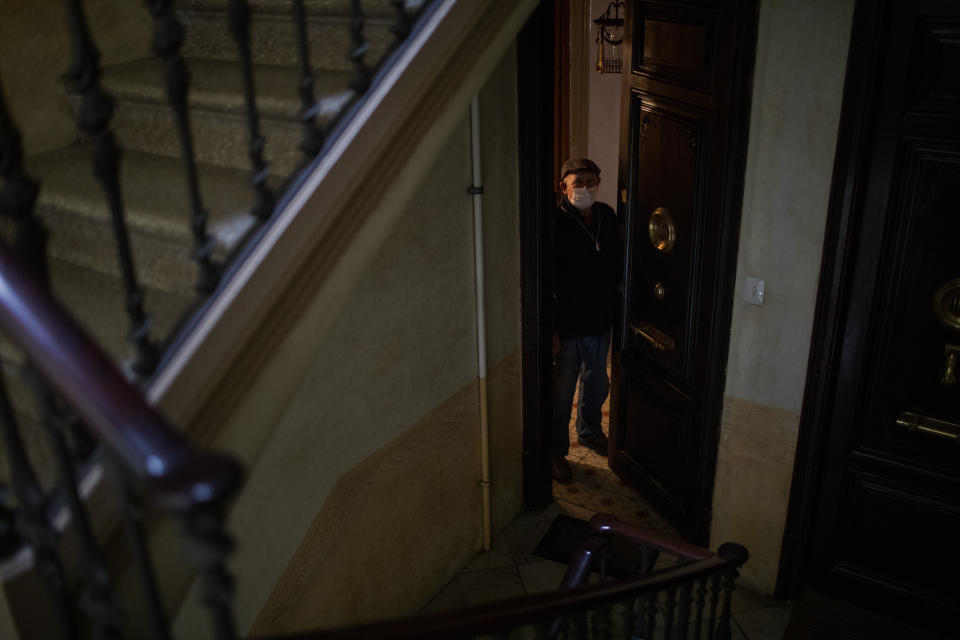 Jose Marcos, 89, waits at his front door for the nurses who tend to his bedridden wife once a week, in Barcelona, Spain, Monday, April 7, 2020. Marcos' son drops off food at the gate, but Marcos doesn't dare go outside on his own for fear he will be infected with the coronavirus. (AP Photo/Emilio Morenatti)