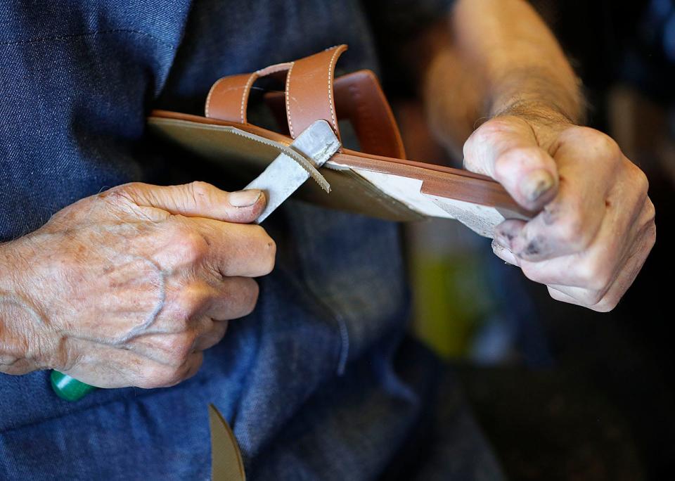 Vincenzo DiRado trims a new leather sole he is fitting to a pair of women's sandals.