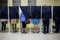 People use voting booths at a pooling station during general elections in Gibraltar, Thursday Oct. 17, 2019. An election for Gibraltar's 17-seat parliament is taking place Thursday under a cloud of uncertainty about what Brexit will bring for this British territory on Spain's southern tip. (AP Photo/Javier Fergo)